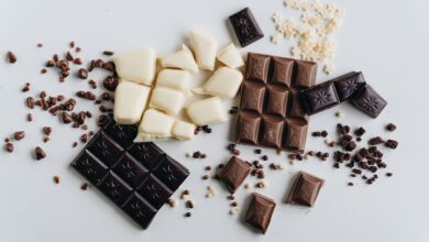 An artistic flat lay of assorted dark, white, and milk chocolate bars with chocolate crumbles.