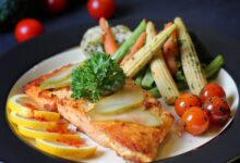 A beautifully plated salmon dish with fresh vegetables and lemon slices, perfect for a gourmet meal.